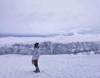 Rear view of man photographing on snow covered landscape