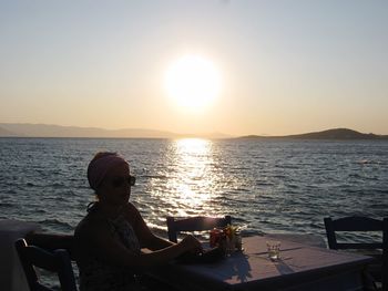 Woman sitting at beach during sunset