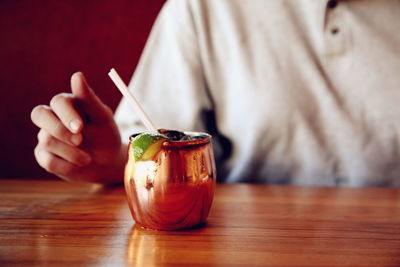 Midsection of woman with moscow mule at table