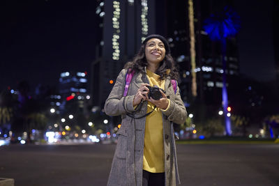 Young woman using mobile phone in city at night