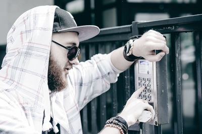 Young man entering password in security system on gate