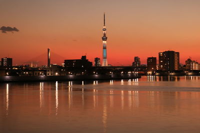 Scenic view of sumida river in city against sky during sunset