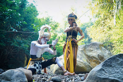 People sitting on rock against trees in forest