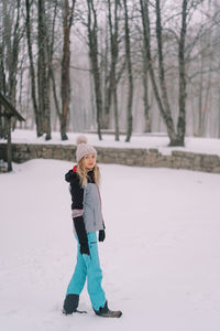 Full length of young woman skiing on snow covered field