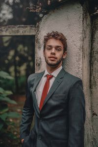 Portrait of young man standing against wall