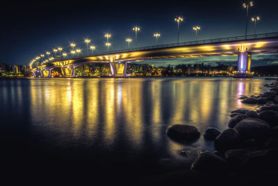 Illuminated bridge over river at night