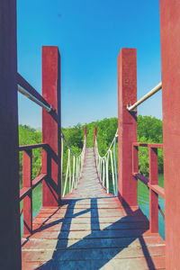 View of wooden bridge against clear blue sky