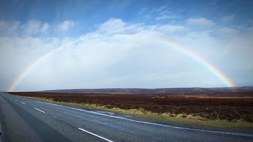 Scenic view of rainbow over mountain against sky