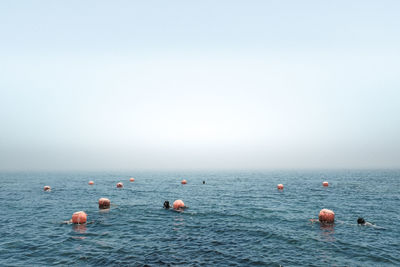Rear view of woman swimming in sea against clear sky