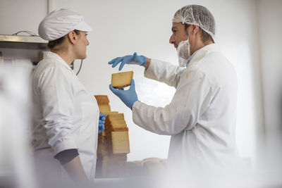 Cheese factory workers testing quality of cheese