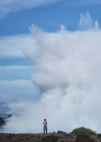 Rear view of man standing on mountain against sky