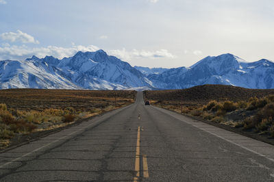 Road leading towards mountains against sky