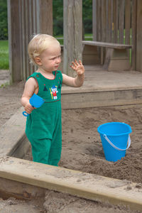 Child baby in sandbox playing with beach toys. girl toddler watching exploring sand on hands. 