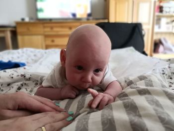 Portrait of cute baby lying on bed at home