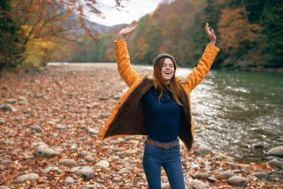 Full length of smiling young woman standing on land during autumn
