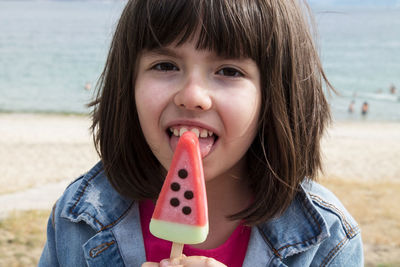 Little girl eating a watermelon ice cream with beach background