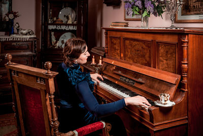 Vintage portrait of a stylish lady in an evening dress sitting at the piano in retro interior 