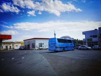Cars on street by buildings against blue sky