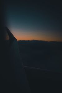 Cropped image of airplane wing against sky during sunset