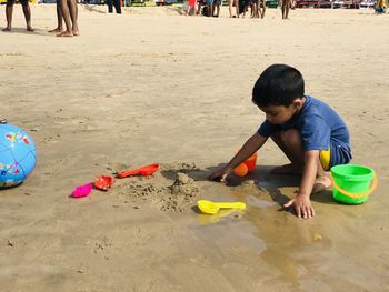 Side view of boy playing with toys on beach during sunny day