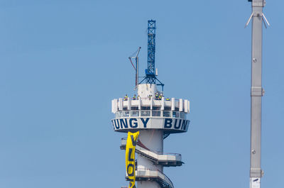 Low angle view of communications tower against clear blue sky