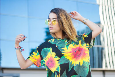 Fashionable young woman wearing top and sunglasses in city