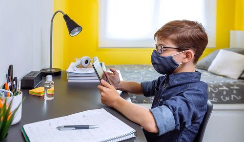 Man using mobile phone while sitting on table