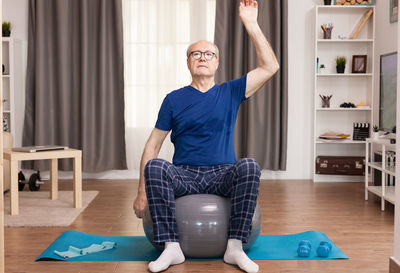 Senior man with hands raised exercising at home