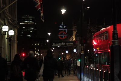 People on illuminated christmas lights in city at night