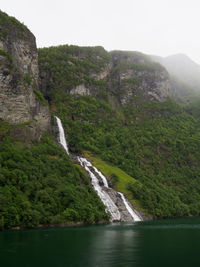 Scenic view of waterfall by mountains against clear sky