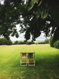 Empty chair on field against sky