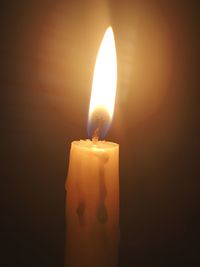 Close-up of lit candle in darkroom