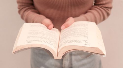 Midsection of woman hands holding book at home