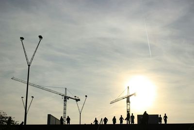 Low angle view of silhouette cranes against sky