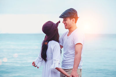 Young couple standing in sea against sky