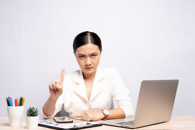 Young woman using mobile phone while sitting on table