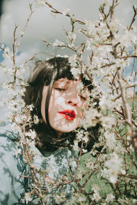 Close-up of woman with eyes closed by plants against sky