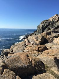 Rocks on beach against clear blue sky