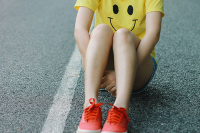 Low section of woman sitting on street