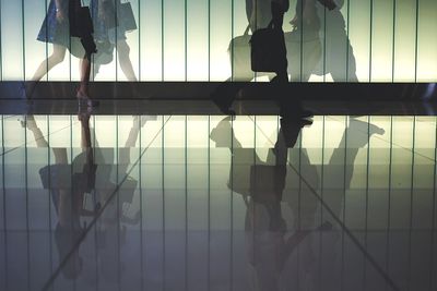 Low section of people walking on tiled floor in building