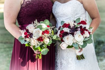 Midsection of woman with bride holding bouquet