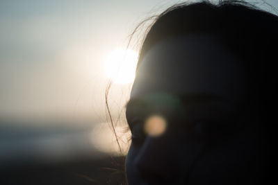 Close-up of woman against bright sun during sunset