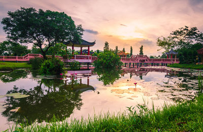 Scenic view of lake by buildings against sky during sunset