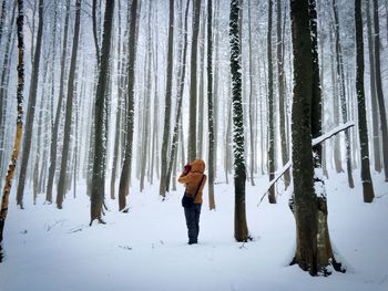 Full length of woman standing in snow covered forest