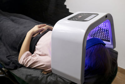 Led light mask for facial skin therapy, care. young woman gets skin rejuvenation light treatment