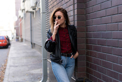 Young woman standing against wall