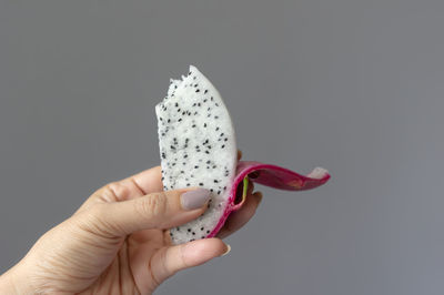 Close-up of hand holding apple against white background