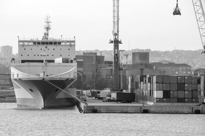 Sailboats moored on harbor by city against clear sky