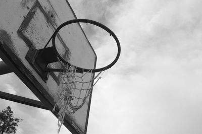 Low angle view of basketball hoop against sky in black and white.