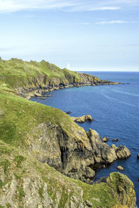 Scenic view of sea by cliff against sky